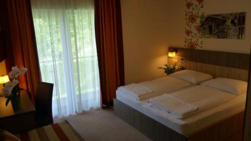 a bedroom with a bed and a large window at Hotel Alta Vista in Neukirchen am Großvenediger