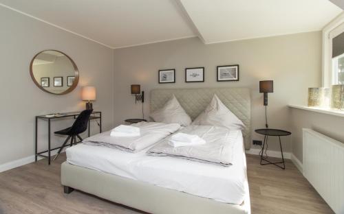 a bedroom with a white bed with a mirror and a desk at Warfthüs in Sankt Peter-Ording
