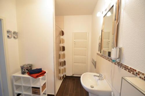 La salle de bains blanche est pourvue d'un lavabo et d'un miroir. dans l'établissement Apartment London, à Mühlhausen