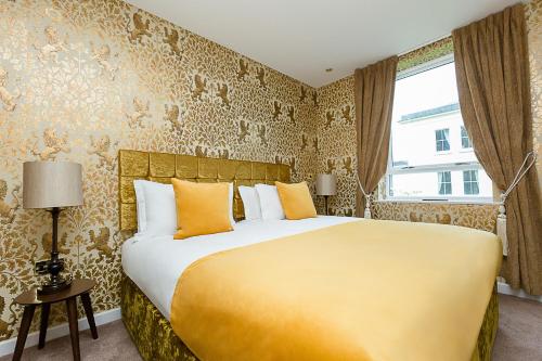 a bedroom with a large bed with yellow pillows at RainHill Hall Hotel in Rainhull