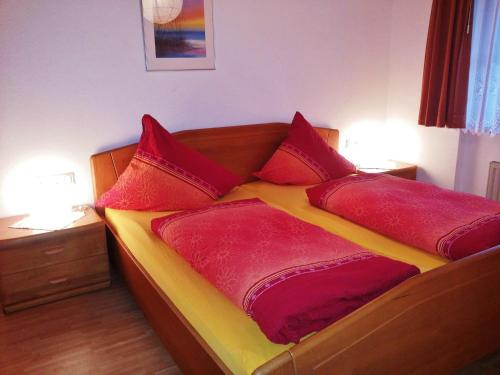 una cama con almohadas rojas en una habitación en Bühlhof Todtnauberg Wohnung 1 en Todtnauberg