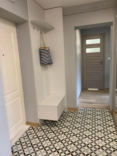 korytarz z białymi drzwiami i czarno-białą podłogą w obiekcie Apartment Nadia w mieście Ełk