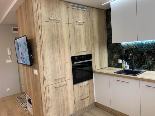 a kitchen with wooden cabinets and a black oven at Apartment Nadia in Ełk