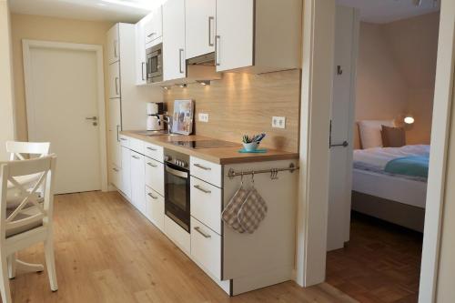 a kitchen with white cabinets and a bed in a room at Hof Wittensee, Seeidyll in Klein Wittensee
