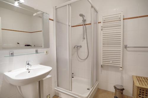 a white bathroom with a sink and a shower at Ostsee-Residenz Whg 12 in Zingst