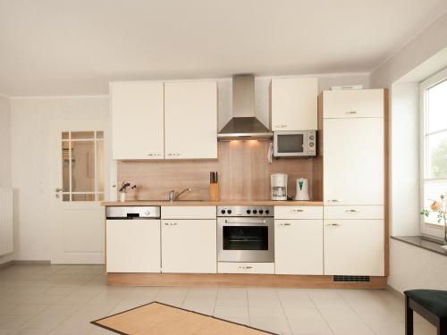a kitchen with white cabinets and a stove top oven at Wohnung 1 in Fehmarn