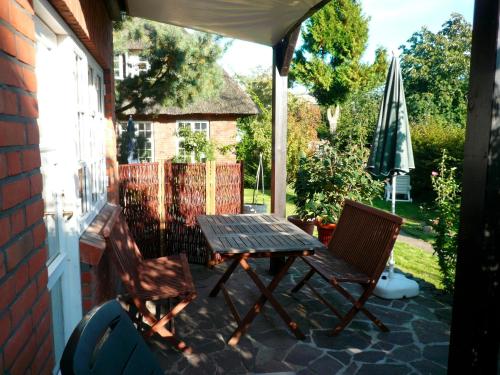un patio con mesa, sillas y sombrilla en Landhaus-Marwede App 3, en Haffkrug