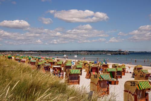 a beach with chairs and umbrellas and people in the water at Landhaus-Marwede App 3 in Haffkrug