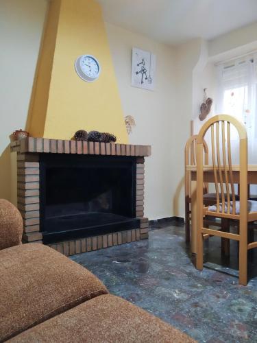 a living room with a fireplace with a clock on the wall at CASA RURAL CELIA con Escape Room in Ayna