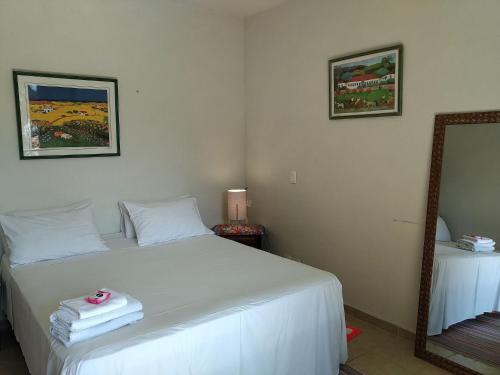 a bedroom with a white bed and a mirror at Elephant GuestHouse Beira Mar - Suítes com Café da Manhã in Ilhabela
