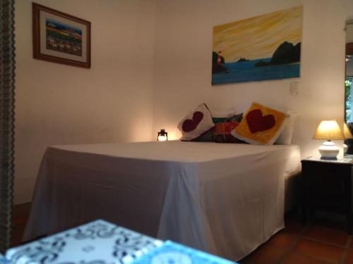 a bed in a room with a white table with pillows at Elephant GuestHouse Beira Mar - Suítes com Café da Manhã in Ilhabela