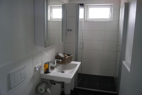 a white bathroom with a sink and a shower at La Domus Superior Osnabrück Lotte in Lotte