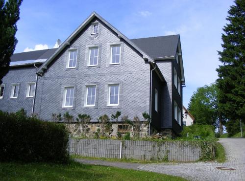 una casa gris con una valla delante de ella en Ferienhaus Gäste Komfort Vesser en Vesser