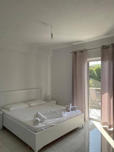 a white bedroom with a bed and a window at Villa Angelina Ksamil in Ksamil
