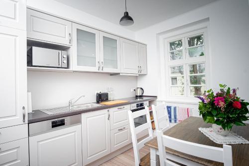 a kitchen with white cabinets and a table with a vase of flowers at Altstadt Apartment in Goslar