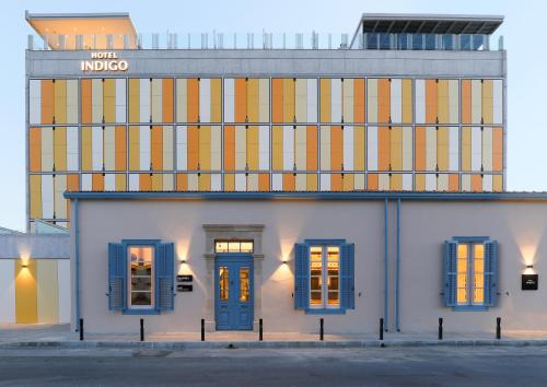 a white building with blue windows and a building with a sign at Hotel Indigo Larnaca by IHG-ADULTS ONLY in Larnaka