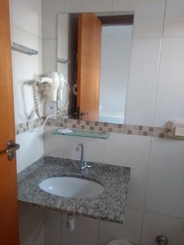 ein Badezimmer mit Waschbecken und Spiegel in der Unterkunft Hotel Flamboiã in Araraquara