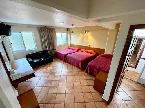 a hotel room with two beds and a chair at HOTEL BUGAMBILIAS in Oaxaca City