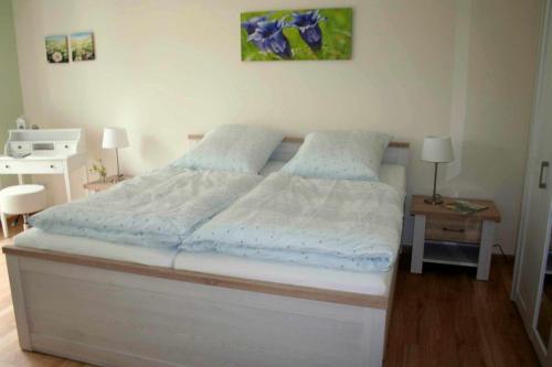 ein Schlafzimmer mit einem weißen Bett mit blauer Bettwäsche in der Unterkunft Lachmöwe App 35 in Dierhagen
