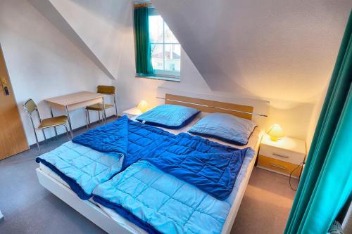 ツィングストにあるAm Deich 18のベッドルーム1室(青いシーツとテーブル付)