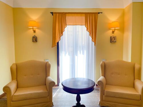two chairs and a table in a room with a window at Hotel La Plumeria in Cefalù