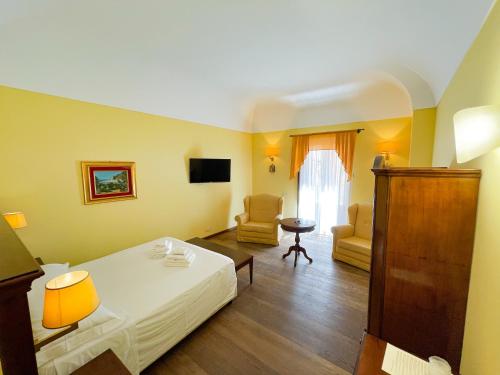 a bedroom with a bed and chairs and a television at Hotel La Plumeria in Cefalù