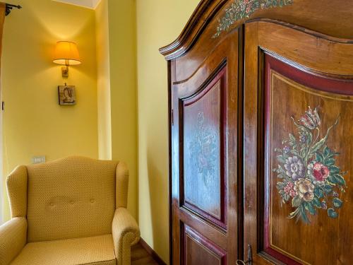 a living room with a chair next to a large wooden cabinet at Hotel La Plumeria in Cefalù