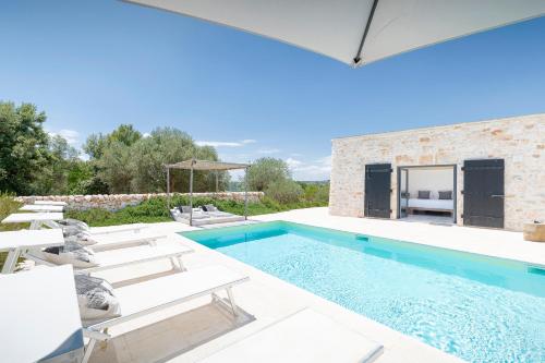 a swimming pool with chairs and a villa at trullo and lamia cinera in Cisternino