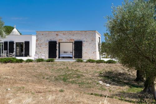 a house on a hill with a tree in the foreground at trullo and lamia cinera in Cisternino