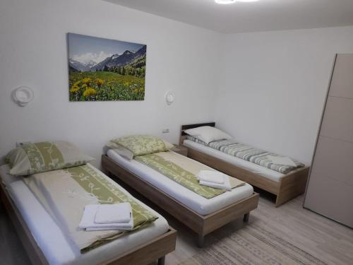 three beds in a room with a painting on the wall at Casa Sannicolau in Sînnicolau Mare