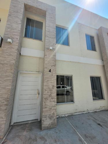 a white building with a white garage door and a car at Sobrado 4 amplo e confortável em condomínio in Corumbá