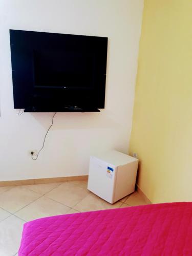 a room with a tv on the wall and a white refrigerator at Hospedaria São Benedito in Guararema