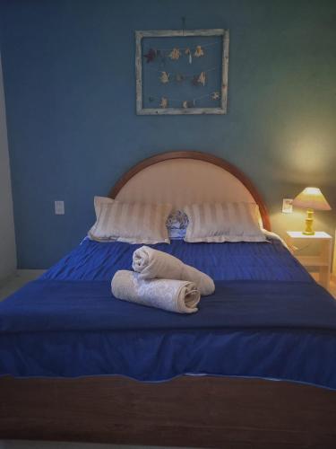 two towels on a blue bed with two pillows at Cabañas Virazon Aguas Dulces in Aguas Dulces