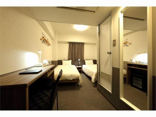 a hotel room with a bedroom with a desk and a bed at Sendai Business Hotel Ekimae - Vacation STAY 71942v in Sendai