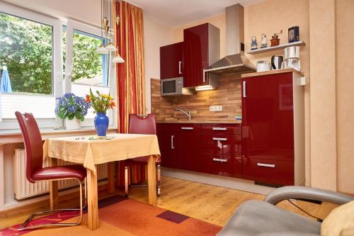 ヴァンガーオーゲにあるOsterdüne 66のテーブル付きのキッチン、赤いキャビネット付きのキッチン