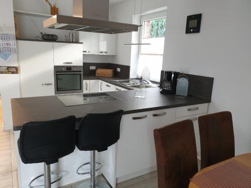 eine Küche mit weißen Schränken und schwarzen Arbeitsplatten in der Unterkunft Ferienwohnung Reinhardt in Oldenburg