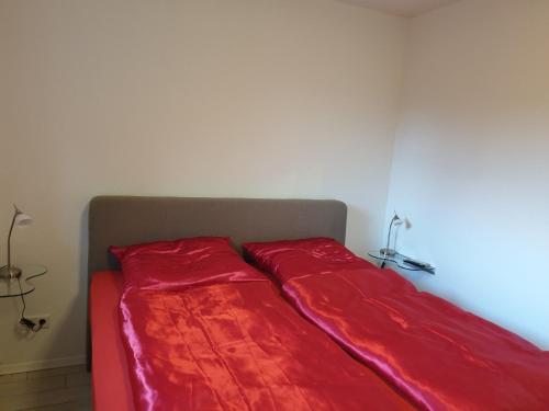 a bed with red sheets sitting in a room at Ferienwohnung Reinhardt in Oldenburg
