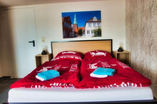 a bed with red sheets and blue pillows on it at Segellast 4 in Lübeck