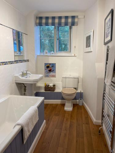 uma casa de banho com uma banheira, um WC e um lavatório. em The Long House em Cirencester