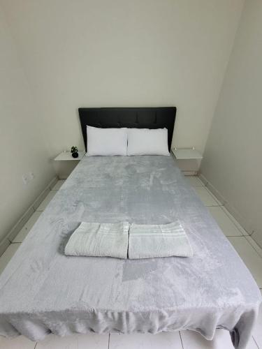 a bed in a white room with a gray blanket at Sobrado 4 amplo e confortável em condomínio in Corumbá