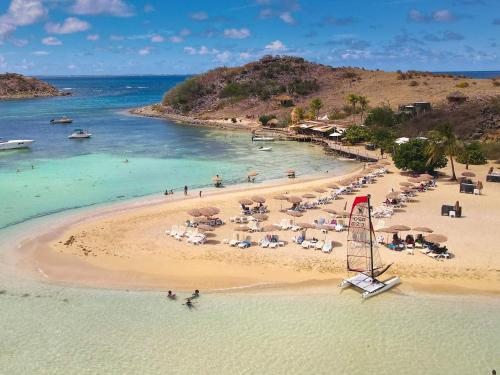 una spiaggia con un mucchio di ombrelloni e persone in acqua di Beautiful suite S14, pool, next to Pinel Island a Cul de Sac