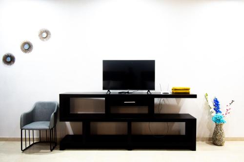a black entertainment center with a tv and a chair at Hotel Casa Tortuga Tulum - Cenotes Park Inclusive in Tulum