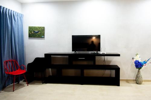 a living room with a television and a red chair at Hotel Casa Tortuga Tulum - Cenotes Park Inclusive in Tulum