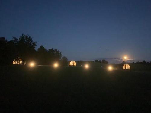 a group of tents in a field at night at Kedras Glamping - Pod tipo nameliai in Prapuntai