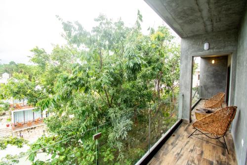 a balcony with two chairs and a tree at Hotel Casa Tortuga Tulum - Cenotes Park Inclusive in Tulum