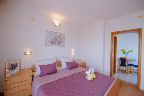 - une chambre dotée d'un lit violet avec un animal rembourré dans l'établissement Vila Maric, à Brist