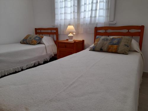 1 dormitorio con 2 camas y mesita de noche con lámpara en Hotel Rincón de Playa en Miramar