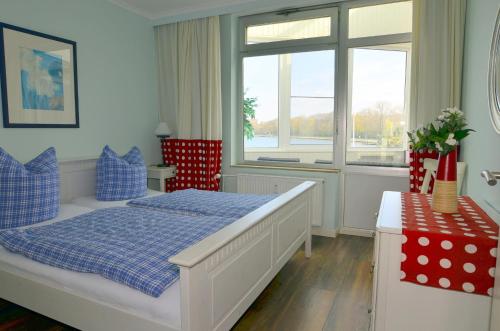 ハイリゲンハーフェンにあるFewo im Haus des Kurgastesのベッドルーム1室(青と赤の枕が備わるベッド1台付)