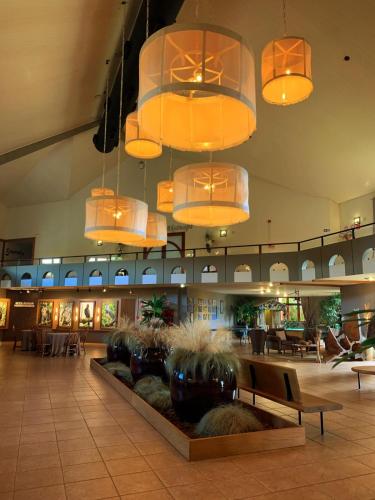 a lobby with several lights and a large lobby with tables at Tenondé Park Hotel in São Miguel das Missões