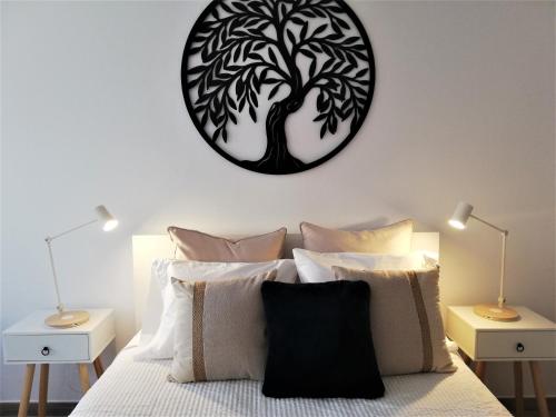 a bedroom with a black and white tree clock on the wall at Casa Paixanita - jacuzzi & terrace downtown Olhao in Olhão